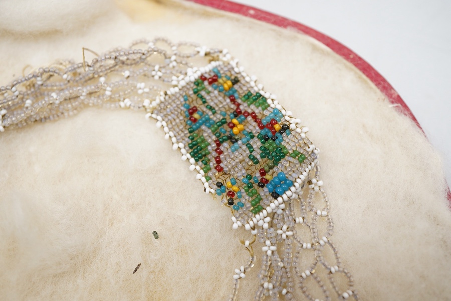A glass bead necklace, early 19th century, intricately composed of woven glass beads depicting panels of butterflies and flowers, together with early 20th century correspondence from the Victorian & Albert Museum discuss